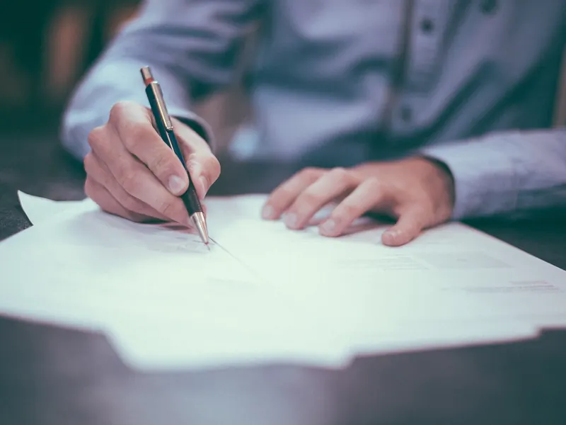 Tangan menandatangani borang dengan pen
